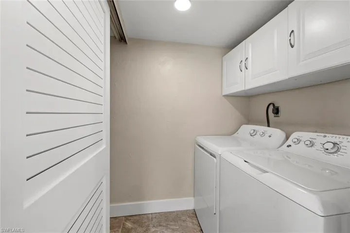 Clothes washing area featuring washer and clothes dryer, cabinets, light tile floors, and hookup for an electric dryer