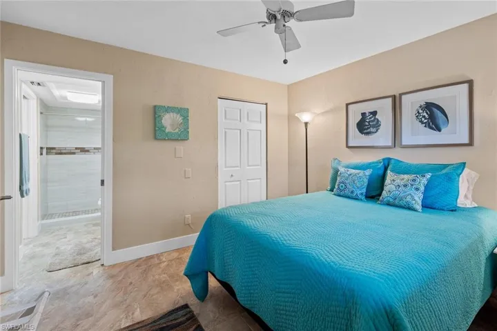 Tiled bedroom with a closet, connected bathroom, and ceiling fan