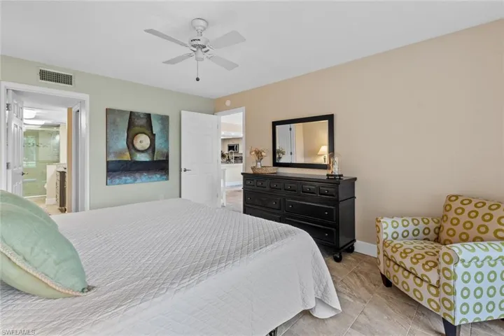 Tiled bedroom featuring ceiling fan and connected bathroom