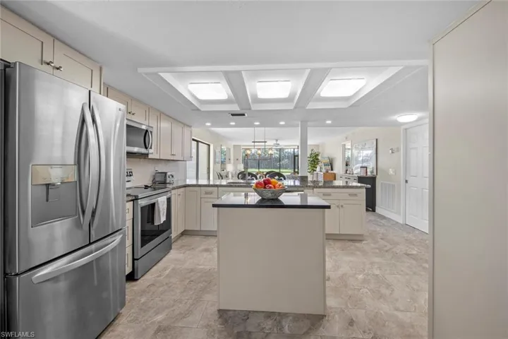 Kitchen with a center island, kitchen peninsula, light tile flooring, and appliances with stainless steel finishes