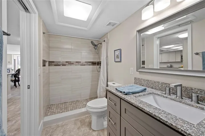 Bathroom featuring a tile shower, tile flooring, oversized vanity, and toilet