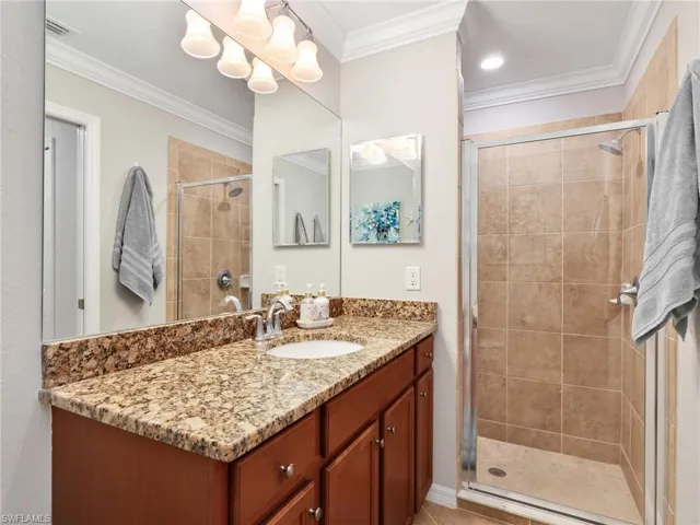 Primary Bathroom with Tile Floors, Granite Countertop, Mirrored Medicine Cabinet, & Tiled Shower with Glass Shower Enclosure