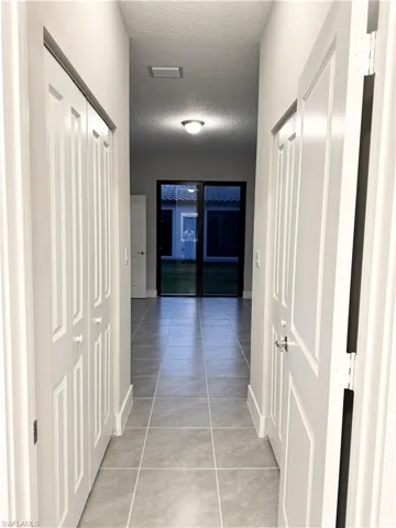 Hallway with light tile patterned flooring and a textured ceiling