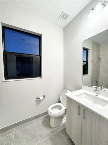 Bathroom featuring tile patterned flooring, vanity, a textured ceiling, and toilet