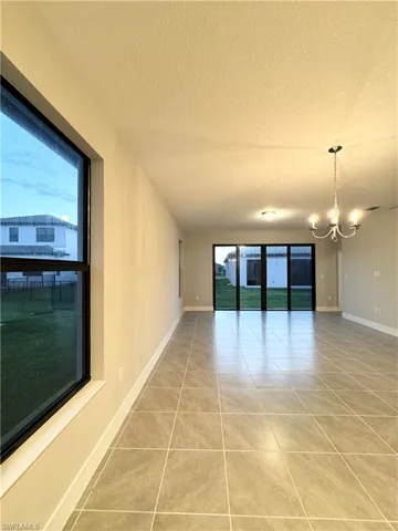 Unfurnished room featuring an inviting chandelier, tile patterned flooring, and a textured ceiling