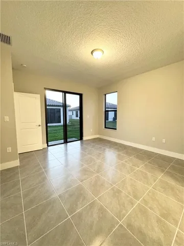 Tiled empty room featuring a textured ceiling