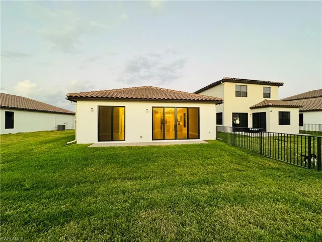 Back of property featuring a lawn and central air condition unit