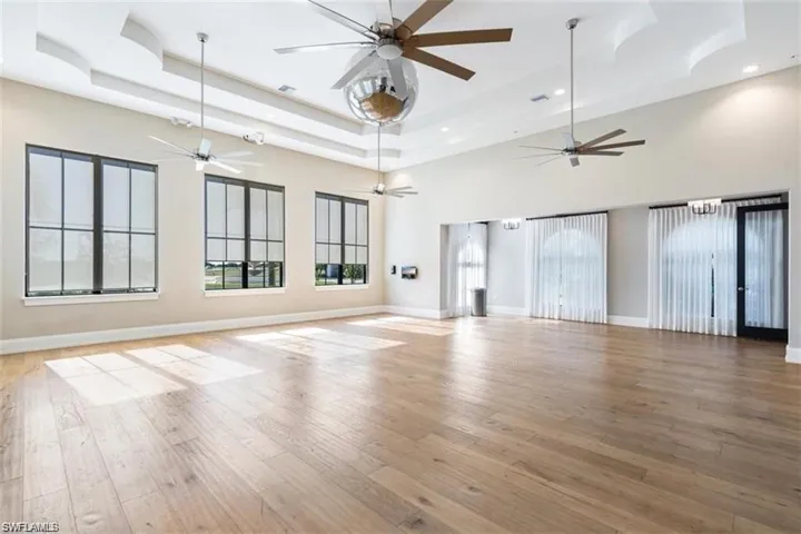 Unfurnished living room with a tray ceiling, light hardwood / wood-style floors, and a high ceiling