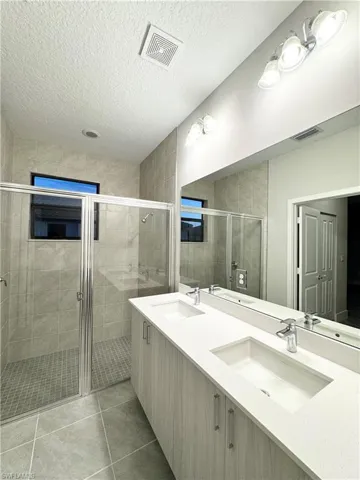 Bathroom with tile patterned floors, vanity, a shower with door, and a textured ceiling