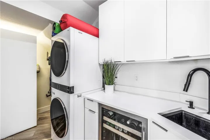 Laundry room featuring new washer/dryer, sink, upper and lower cabinetry, beverage refrigerator and additional storage!