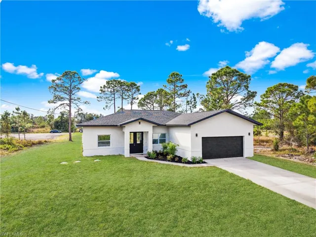 Ranch-style house featuring an attached garage, stucco siding, and a front yard