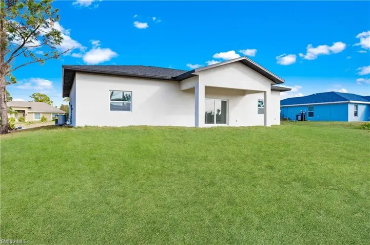 Back of house with stucco siding and a lawn