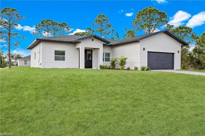 Ranch-style house featuring an attached garage, stucco siding, and a front yard