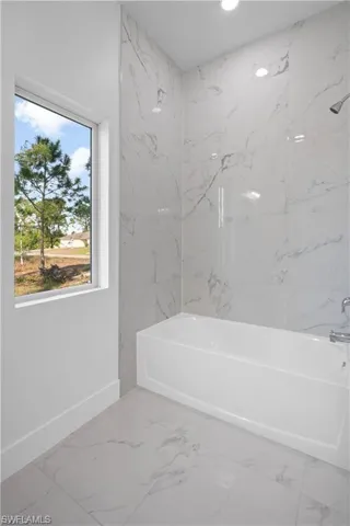 Full bath with light marble finish floors,  shower combination, and recessed lighting