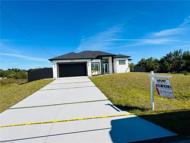 View of front facade featuring a front yard and a garage