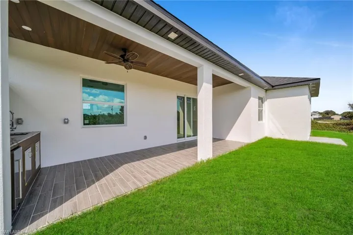 Rear view of house featuring a yard, ceiling fan, and a patio area