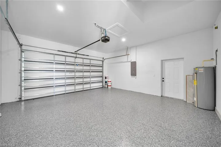 Garage featuring water heater, a garage door opener, and electric panel