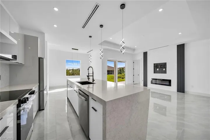 Kitchen with pendant lighting, sink, an island with sink, white cabinets, and appliances with stainless steel finishes