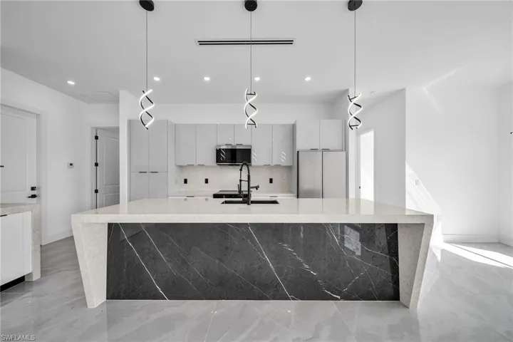 Kitchen with stainless steel appliances, decorative light fixtures, and a spacious island