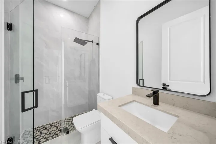 Bathroom featuring an enclosed shower, vanity, and toilet