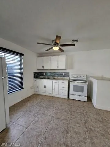 Kitchen featuring white cabinets, white appliances, and ceiling fan