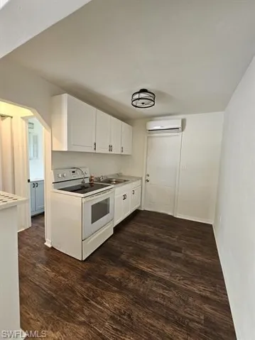 Kitchen featuring white cabinetry, white electric stove, dark wood-style flooring, and light countertops