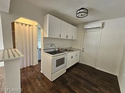 Kitchen featuring white cabinetry, white electric range, dark wood-style floors, and light countertops