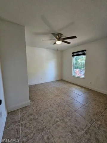 Empty room with tile patterned floors, a textured ceiling, and ceiling fan