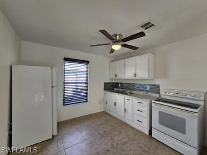 Kitchen with white appliances, white cabinets, ceiling fan, light tile patterned floors, and light countertops