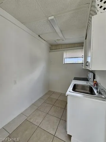 Laundry room with light tile patterned floors and a paneled ceiling