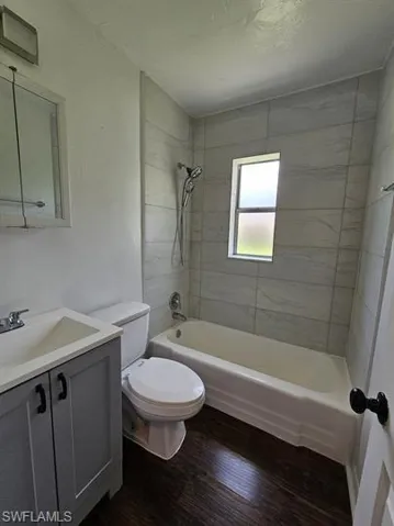Bathroom with shower / bath combination, vanity, and dark wood-style flooring