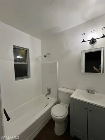 Bathroom with shower / tub combination, vanity, and dark wood-style floors