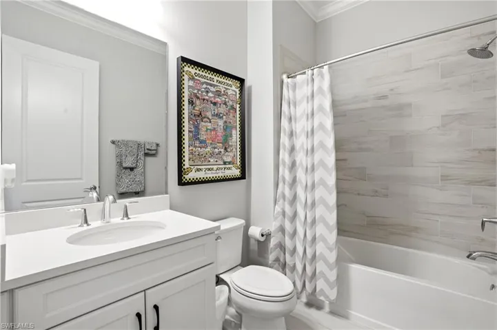 Full bath with ornamental molding, vanity, and shower / bathtub combination with curtain