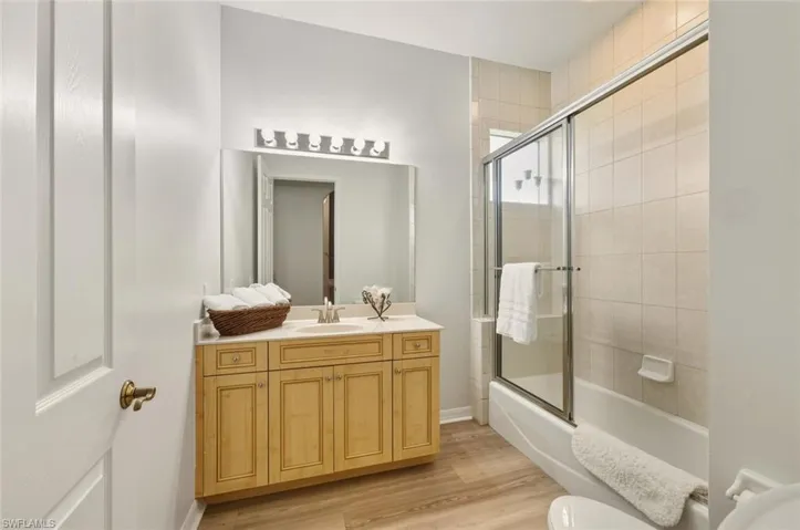 Full bathroom featuring vanity, bath / shower combo with glass door, and light wood-style floors