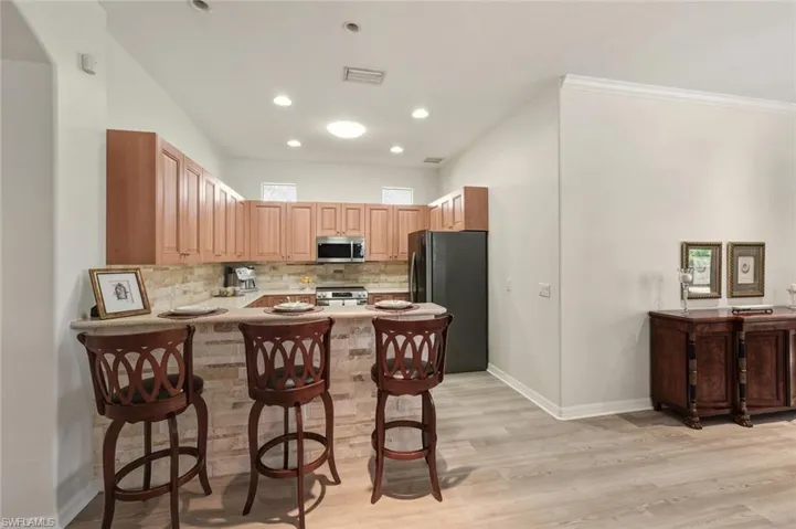 Kitchen with appliances with stainless steel finishes, a kitchen bar, tasteful backsplash, a peninsula, and light wood-style flooring