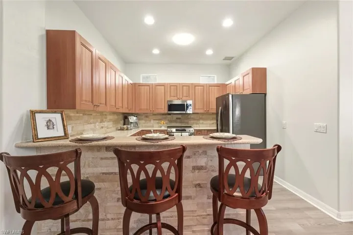 Kitchen featuring appliances with stainless steel finishes, tasteful backsplash, a peninsula, a breakfast bar area, and light countertops