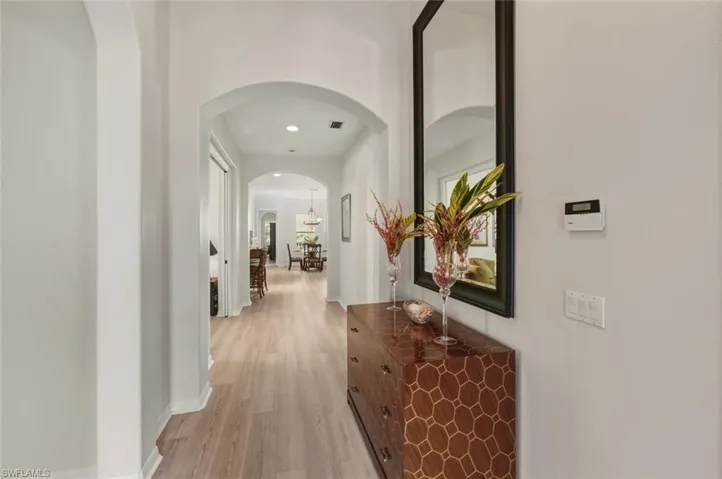 Corridor featuring light wood-style flooring, arched walkways, and recessed lighting