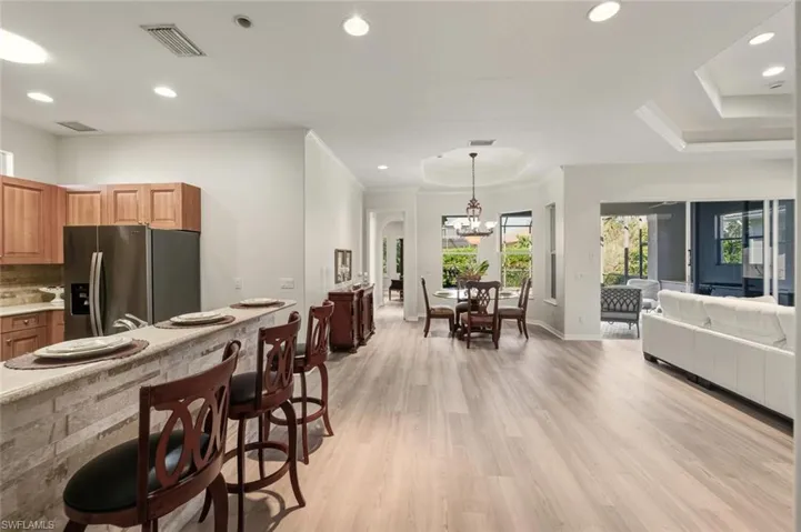 Kitchen featuring a kitchen breakfast bar, open floor plan, stainless steel fridge, hanging light fixtures, and light wood finished floors