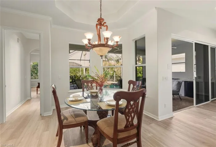 Dining space featuring healthy amount of natural light, ornamental molding, a chandelier, arched walkways, and light wood-type flooring