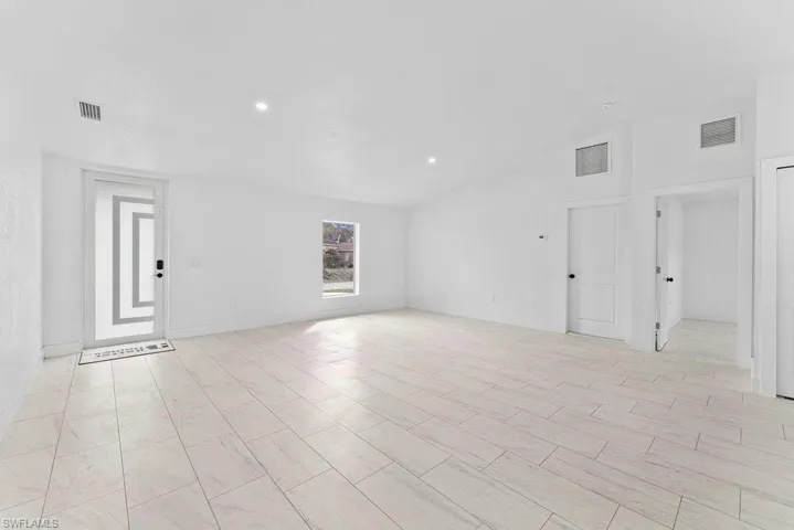 Spare room featuring vaulted ceiling and baseboards
