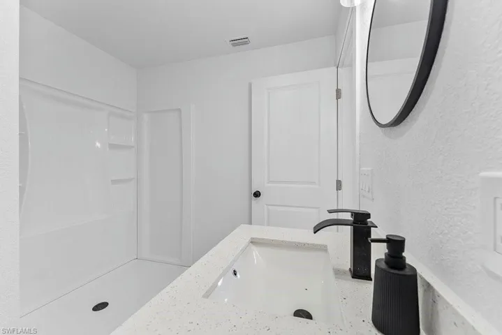 Bathroom featuring vanity, a stall shower, and a textured wall