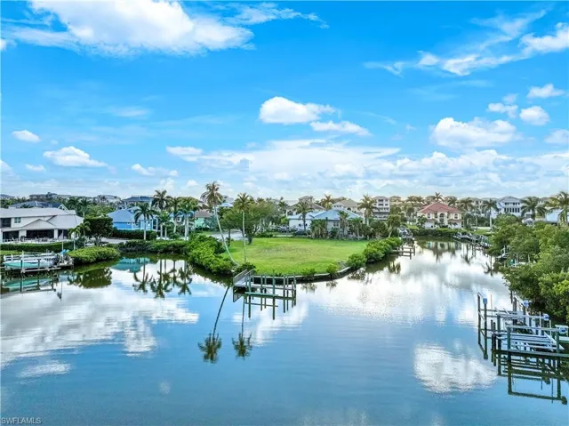Water view with a boat dock, boat lift, and nearby suburban area