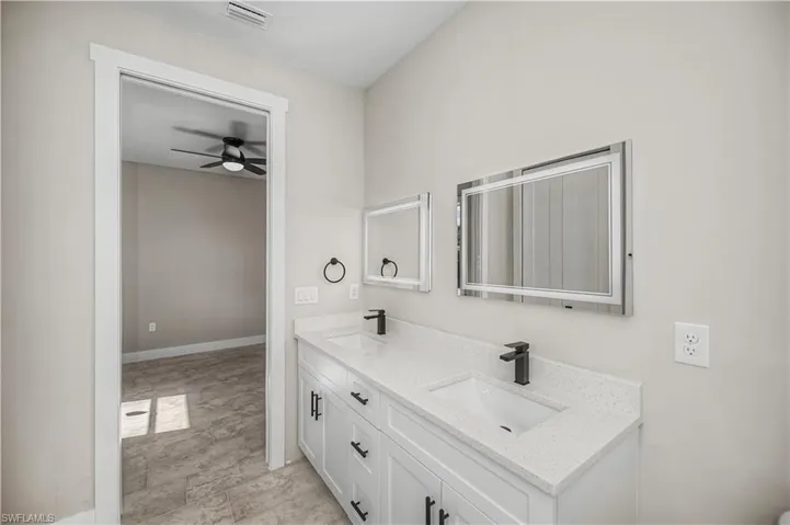Full bathroom featuring double vanity and ceiling fan