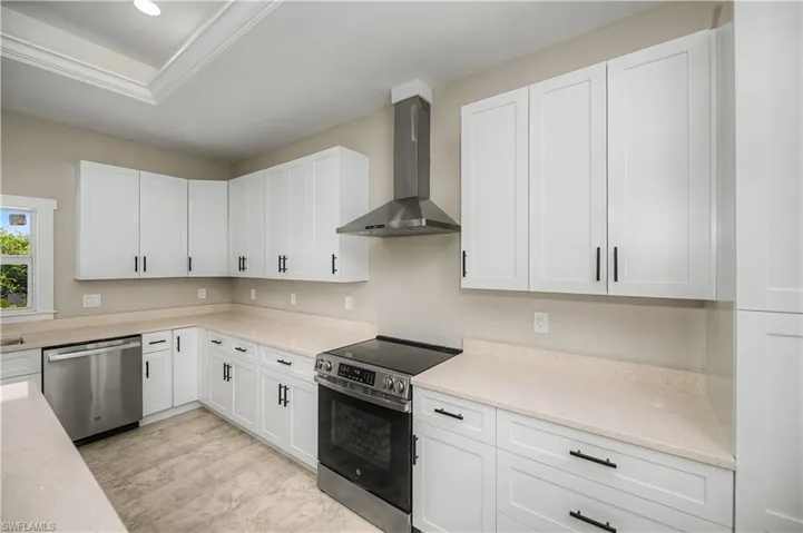 Kitchen with stainless steel appliances, white cabinetry, light stone counters, and crown molding