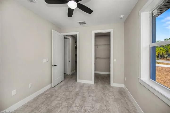 Unfurnished bedroom featuring a walk in closet and ceiling fan
