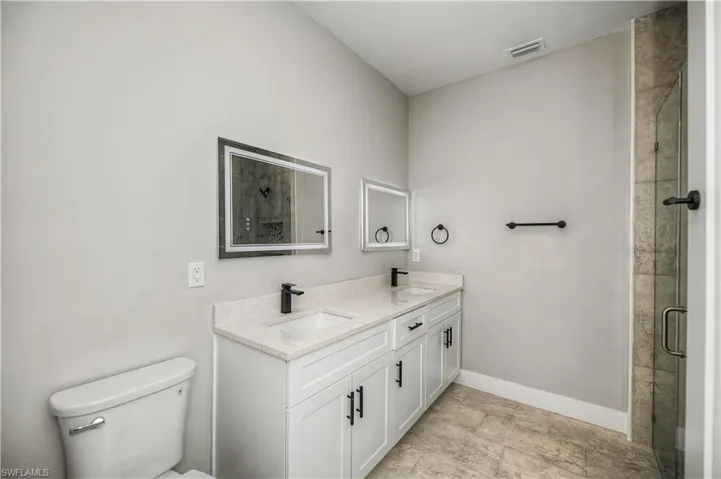 Bathroom featuring double vanity and a stall shower
