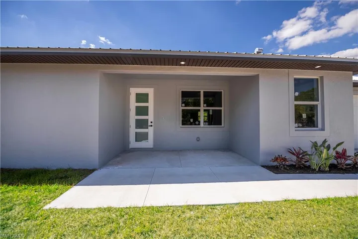 Doorway to property featuring stucco siding, a patio area, and a yard