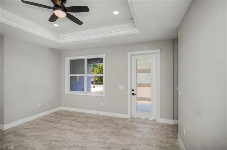 Unfurnished room featuring a raised ceiling, ceiling fan, and recessed lighting