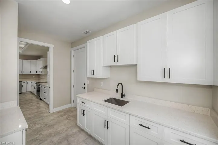 Kitchen featuring white cabinetry, light stone countertops, and stainless steel range