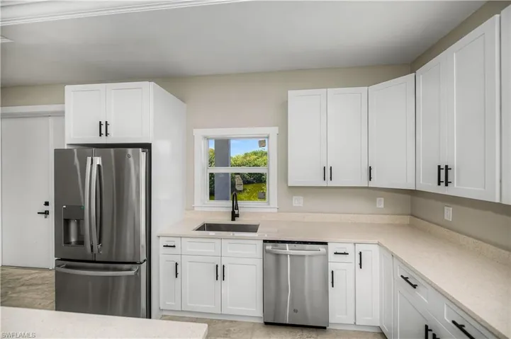 Kitchen featuring stainless steel appliances, white cabinetry, and light stone counters